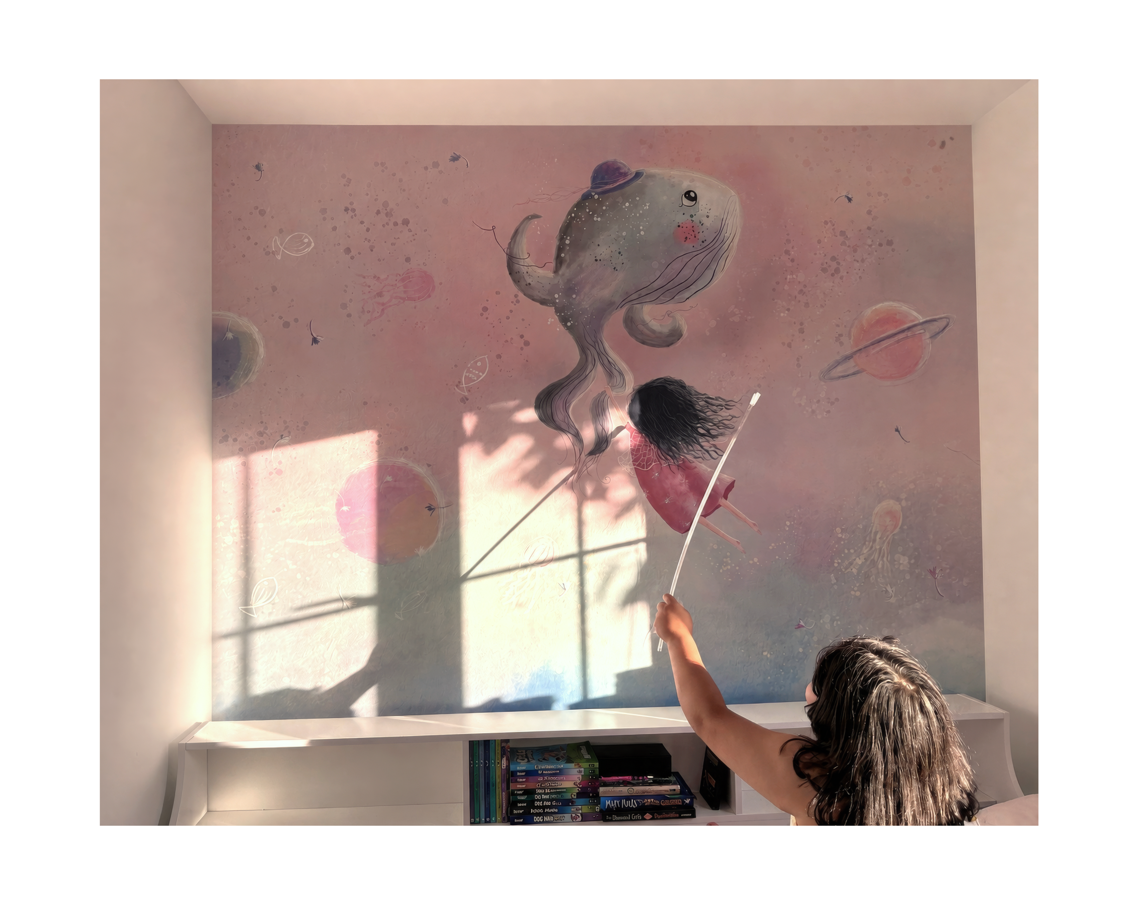 Woman painting a large mural of a fish and a girl with a wand on a wall.
