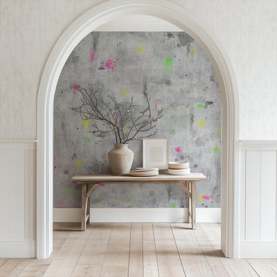 Decorative wall with abstract pattern, table with vase and plates, archway leading to room.