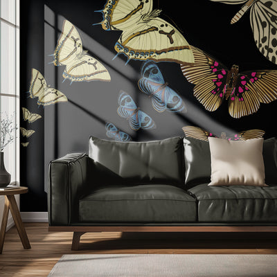 Black leather sofa with decorative pillows in a room with butterfly-themed wallpaper.