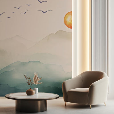 Modern living room with a beige armchair, round coffee table, and wall mural of mountains and sun.
